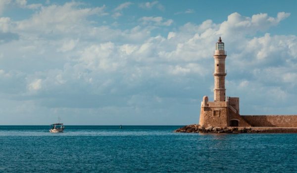 Faro in pietra, cielo e mare con barca sullo sfondo